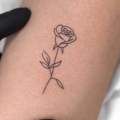 a single rose tattoo on the thigh with black lines in it's center piece