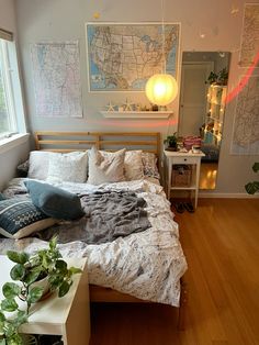 a bed room with a neatly made bed next to a window and a plant on the floor