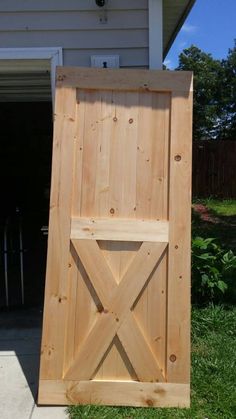 a wooden door sitting in the grass next to a house