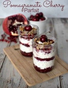 two desserts with cherries and yogurt are on a cutting board next to a pomegranate cherry parfait