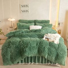 a bed covered in green fluffy blankets and pillows