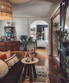 a living room filled with furniture and a fire place next to a wooden floor covered in plants