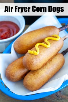 two hotdogs with ketchup and mustard sitting on a plate next to dipping sauce