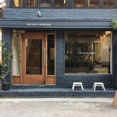 the outside of a coffee shop with two benches in front