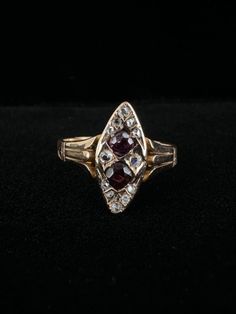 a gold ring with two red stones in the middle and white diamonds on each side