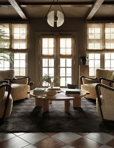 a living room filled with furniture next to two large windows covered in shades of light