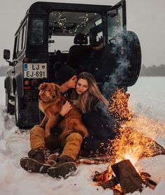 two people sitting in front of a truck with their dog