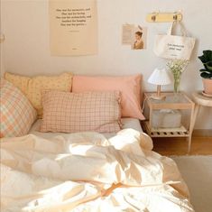 a bed with lots of pillows on top of it next to a table and potted plant