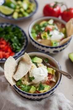 three bowls filled with different types of food next to tomatoes and avocado on a table