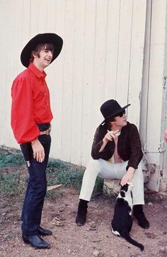 two men in cowboy hats are sitting next to a cat