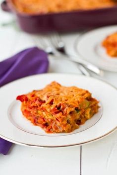 a white plate topped with lasagna covered in sauce