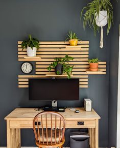 a wooden desk topped with a computer monitor next to a potted plant on top of it