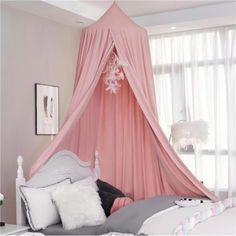 a pink canopy bed with pillows and blankets