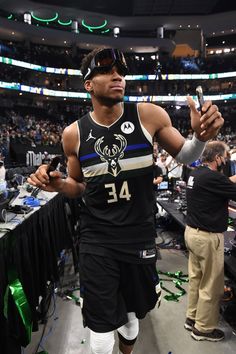 a man standing in the middle of a basketball court holding a cell phone up to his ear