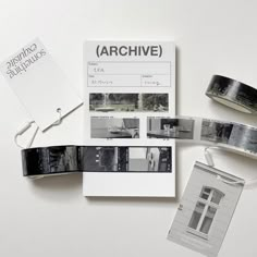 an assortment of black and white photographs on a table next to tape, scissors and other items