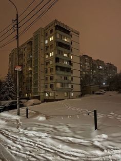 an apartment building is lit up at night in the snow covered area with no cars