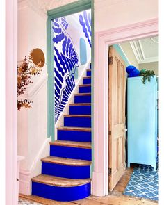 a blue and white staircase leading up to a pink room with an aqua refrigerator in the background