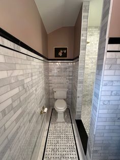 a white toilet sitting inside of a bathroom next to a walk in shower stall with tiled walls