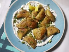 a blue plate topped with food on top of a white and blue table cloth next to a fork