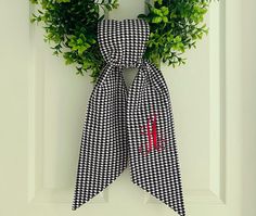 a black and white checkered bow hangs on the front door with a monogrammed wreath