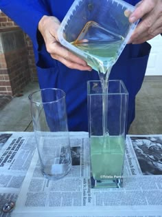 a person pouring liquid into two glasses on top of a newspaper page with another glass next to it