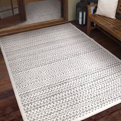 a white rug sitting on top of a wooden floor next to a bench and door