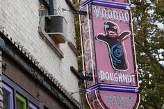 a neon sign on the side of a building that says voodoo doughnut and cafe at the corner