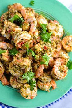 a blue plate topped with cooked shrimp and garnished with parsley