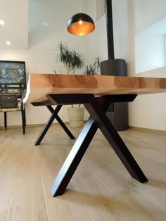 a wooden table sitting on top of a hard wood floor next to a potted plant