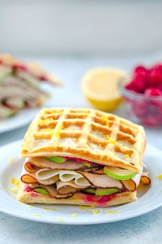 a waffle sandwich on a plate with raspberries and lemons in the background