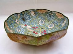 a decorative bowl with birds and flowers painted on the inside, sitting on a white surface