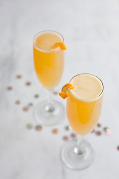 two glasses filled with orange juice and garnished with an orange bow on the rim