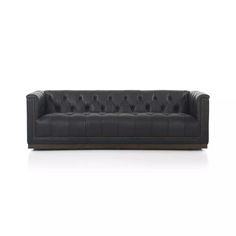 a black leather couch with buttons on the back and arms, sitting in front of a white background