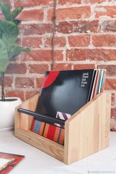 a wooden magazine holder with magazines in it on a table next to a brick wall