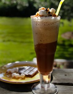 there is a drink with marshmallows in it and a plate on the table