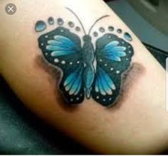 a blue butterfly with drops of water on it's wings is sitting on the arm