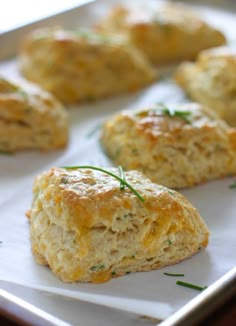 some biscuits are sitting on a tray with green sprigs in the top corner