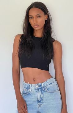 a woman in jeans and a crop top posing for the camera with her hands on her hips