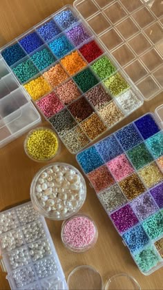 there are many different colors of beads in the trays on the table next to each other