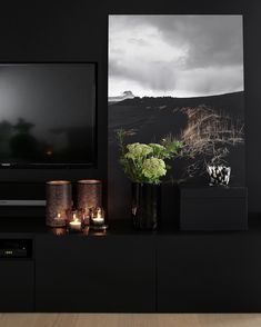 a black entertainment center with candles, vases and pictures on the wall behind it