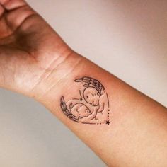 a small tattoo on the wrist of a woman with an angel and baby in her arms