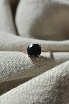 a black diamond ring sitting on top of a white cloth covered couch with it's shadow