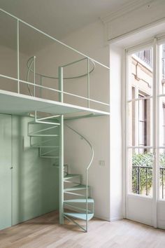 a spiral staircase in an empty room next to a window