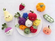 small crocheted fruits and vegetables on a white plate with faces drawn on them