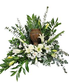 a vase filled with white flowers and greenery next to a planter on top of a table