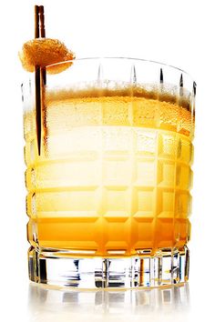 a tall glass filled with orange juice and an orange peel sticking out of the top