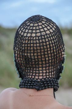 the back of a woman's head wearing a black netted hat with beads