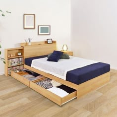 a bed with two drawers underneath it in a white room next to a wooden floor