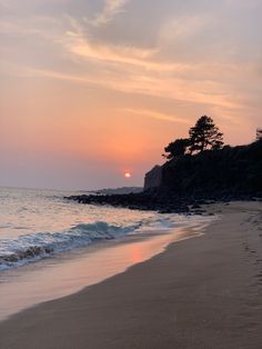 the sun is setting over the water at the beach with waves coming in to shore