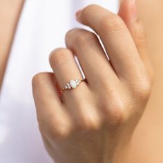 a woman's hand wearing a gold ring with three small white stones on it